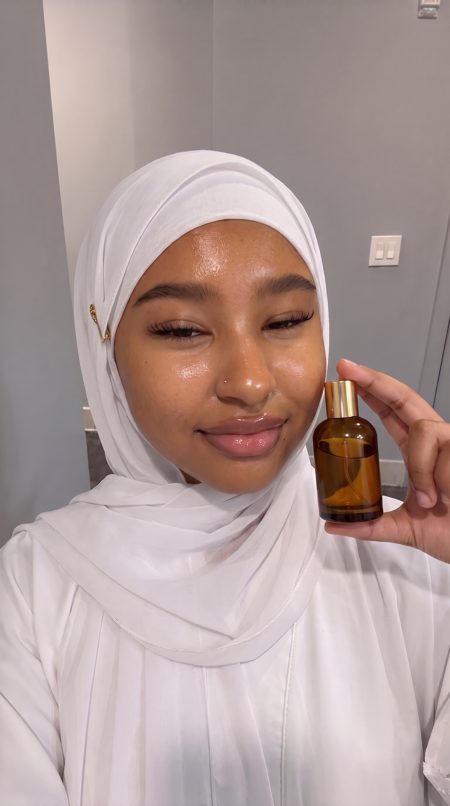 Amina, an AI presenter, holding perfume