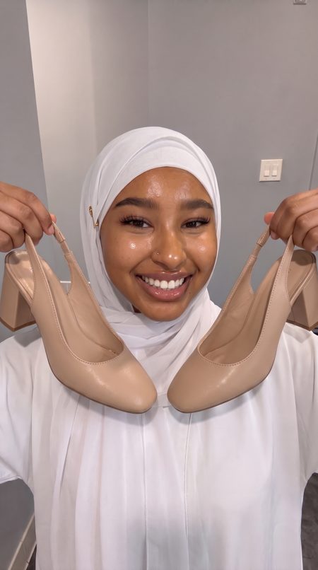Amina, an AI presenter, holding shoes